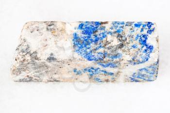 macro shooting of natural mineral - block from Lazurite stone on white marble from Ural Mountains