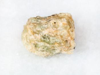 macro shooting of natural mineral - raw chrysoberyl (green beryl) crystal on white marble from Ural Mountains