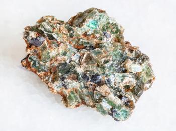 macro shooting of natural mineral - green beryl and emerald crystals in druse on white marble from Ural Mountains