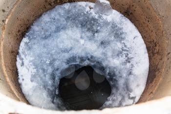 top view of frozen water surface and ice hole in well in cold winter day