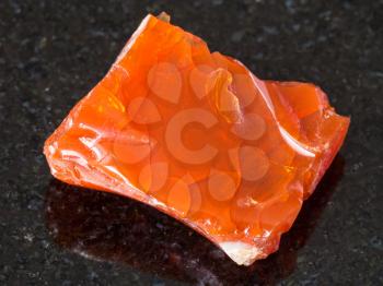 macro shooting of natural mineral - rough fire opal gem stone on black granite from Ural Mountains