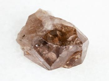 macro shooting of natural mineral - raw smoky quartz crystal on white marble from Ural Mountains