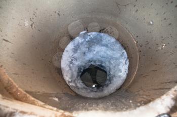 top view of frozen water surface and ice hole in concrete well in cold winter day
