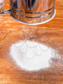 cooking of pie - flour pouring through sifter on wooden board