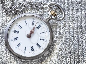 old pocket watch on silver cloth background close up