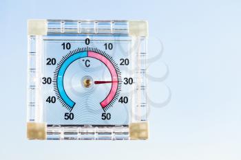 view of outdoor thermometer on home window and blue sky in hot sunny morning