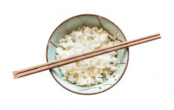 top view of chopsticks above cup with boiled rice isolated on white background