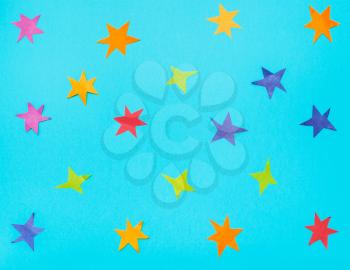 many stars cut from colour papers on blue turquoise pastel paper