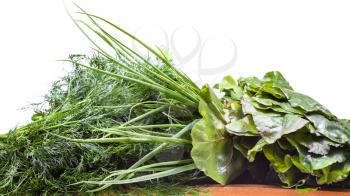 wet fresh bundles of beet greens, scallions and dill on wooden table isolated on white background