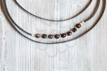 top view of bone beads in handmade necklace from leather strips on gray wooden board