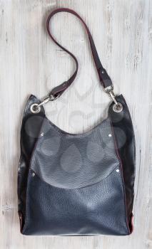 handcrafted gray leather handbag with big pocket on gray wooden table