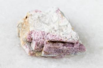 macro photography of sample of natural mineral from geological collection - raw pink Tourmaline mineral in feldspar and quartz rock from Kalba Range, Kazakhstan on white marble background