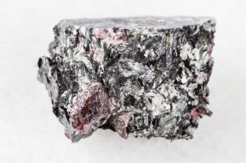 macro photography of sample of natural mineral from geological collection - raw red Garnet crystals in Biotite rock from Yelovyy Navolok, Shueretskoye deposit, Karelia, Russia on white marble