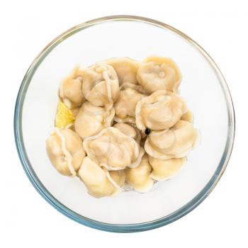 top view of boiled Pelmeni (russian dumplings filled with minced meat) with butter in glass bowl isolated on white background