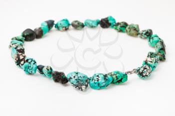 string of beads from natural tumbled dyed howlite gemstone on white paper background