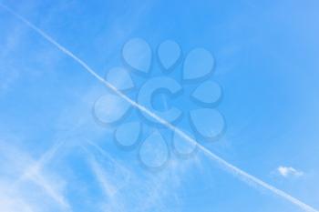 contrail and cirrus clouds in blue sky on autumn day