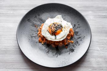 korean cuisine - above view of Kimchi bokkeum bap (fried rice with kimchi, beef and fried egg) on black plate on wooden board