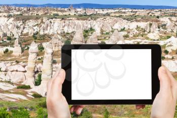 travel concept - tourist photographs of valley with fairy chimney rocks in Goreme National Park in Cappadocia in Turkey on smartphone with empty cutout screen with blank place for advertising