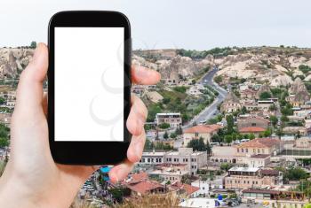 travel concept - tourist photographs of road in modern residential district in Goreme town in spring in Turkey on smartphone with empty cutout screen with blank place for advertising