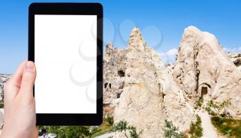 travel concept - tourist photographs of ancient cave monastic settlement near Goreme town in Cappadocia in spring in Turkey on smartphone with empty cutout screen with blank place for advertising