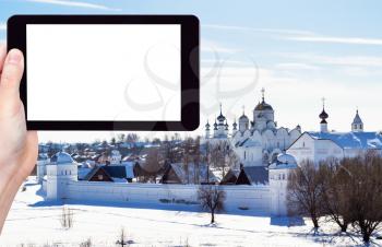 travel concept - tourist photographs of The Convent of the Intercession (Pokrovsky Monastery) in Suzdal town in winterof Russia on smartphone with cutout screen with blank place for advertising