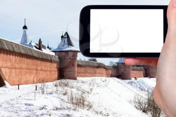 travel concept - tourist photographs of walls of Monastery of Our Savior and St Euthymius in Suzdal town in winter of Russia on smartphone with cutout screen with blank place for advertising