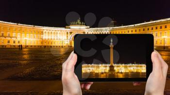 travel concept - tourist photographs of Palace Square with Alexander Column and Winter Palace in Saint Petersburg city in Russia on smartphone in night