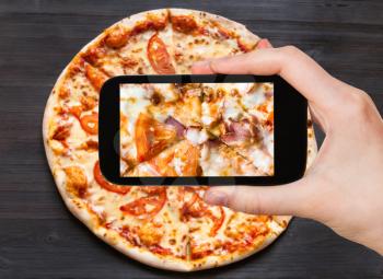 travel concept - visitor photographs of filling of Pizza with Bacon and Tomatoes close up on smartphone