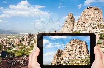travel concept - tourist photographs of rock-cut Uchisar castle in Cappadocia on smartphone in Turkey in spring