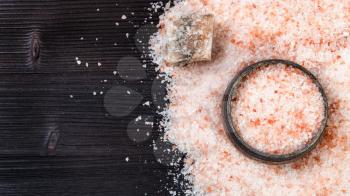 top view of silver salt cellar, raw natural pink Halite mineral and grained Himalayan Salt on dark brown wooden board