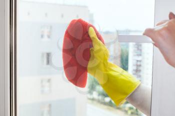 hand cleans window glass of urban apartment house by orange rag