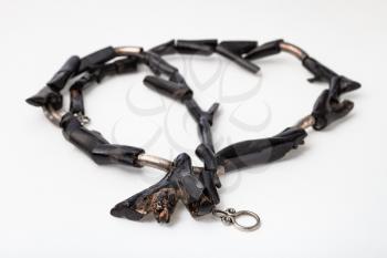 coiled necklace from polished black coral twigs on white paper background