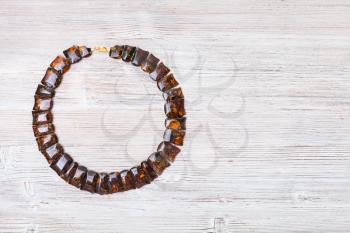 top view of polished amber necklace on gray wooden board with copyspace