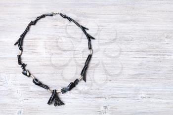 top view of black coral necklace on gray wooden board with copyspace