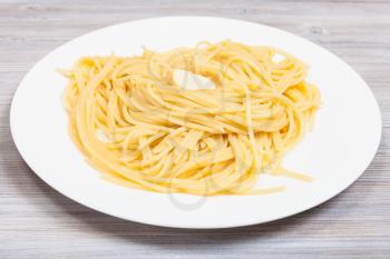 italian cuisine - spaghetti al burro (pasta with butter) on white plate on gray wooden table