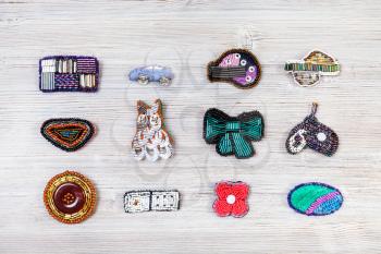 needlecraft background - top view of various handcrafted embroidered brooches on gray wooden board