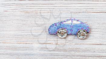 needlecraft background - top view of handcrafted car brooch embroidered by blue silk embroidery threads with clasp buttons on gray wooden board with copyspace