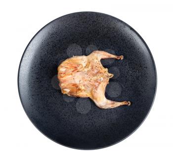 top view of roasted whole flattened quail on black plate isolated on white background