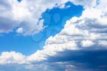 large rainy clouds in blue sky on sunny spring day