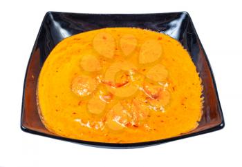 Indian cuisine - portion of Chicken tikka masala (pieces of roasted marinated chicken in spicy curry creamy sauce) in black bowl isolated on white background