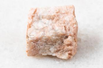 closeup of sample of natural mineral from geological collection - rough Feldspar rock on white marble background