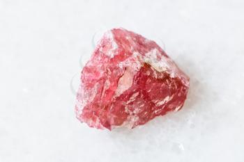 closeup of sample of natural mineral from geological collection - unpolished Rhodonite crystal on white marble background from Morro da Mina mine, Conselheiro Lafaiete, Minas Gerais, Brazil