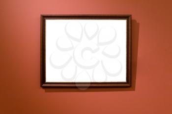 narrow brown wooden picture frame with cutout canvas on dark red wall