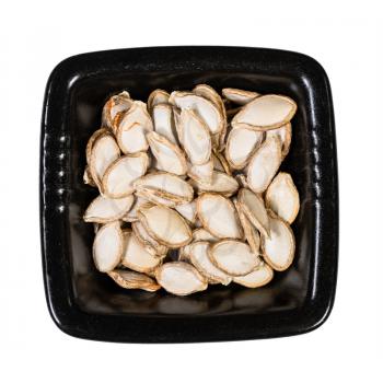 top view of whole pumpkin seeds in black bowl isolated on white background