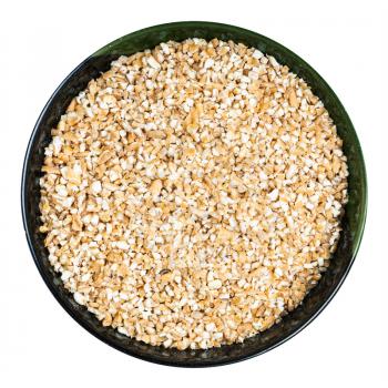 top view of wheat groats (crushed partly hulled wheat grains) in round bowl isolated on white background