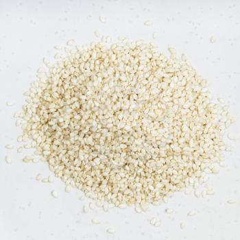 top view of pile of white sesame seeds close up on gray ceramic plate