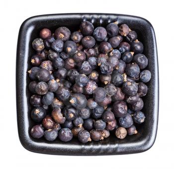 top view of dried juniper berries in black bowl isolated on white background