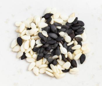 top view of pile of black and white mixed sesame seeds close up on gray ceramic plate