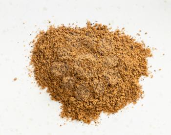 top view of pile of nutmeg powder close up on gray ceramic plate