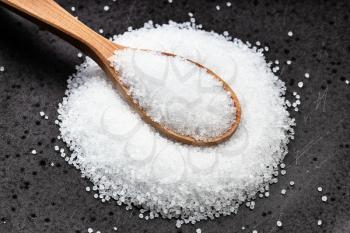 above view of wooden spoon with crystalline fructose close up on black ceramic plate